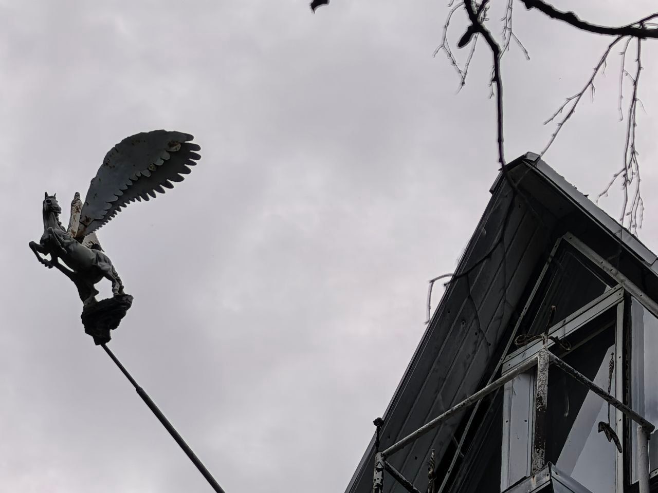 Флюгер в виде крылатого коня Пегаса на фоне неба и грани крыши